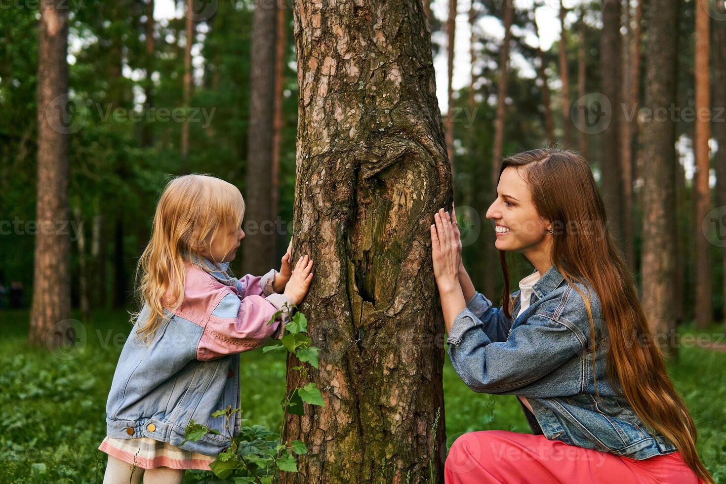 woman playing with a child in the forest, hiding behind a tree photo