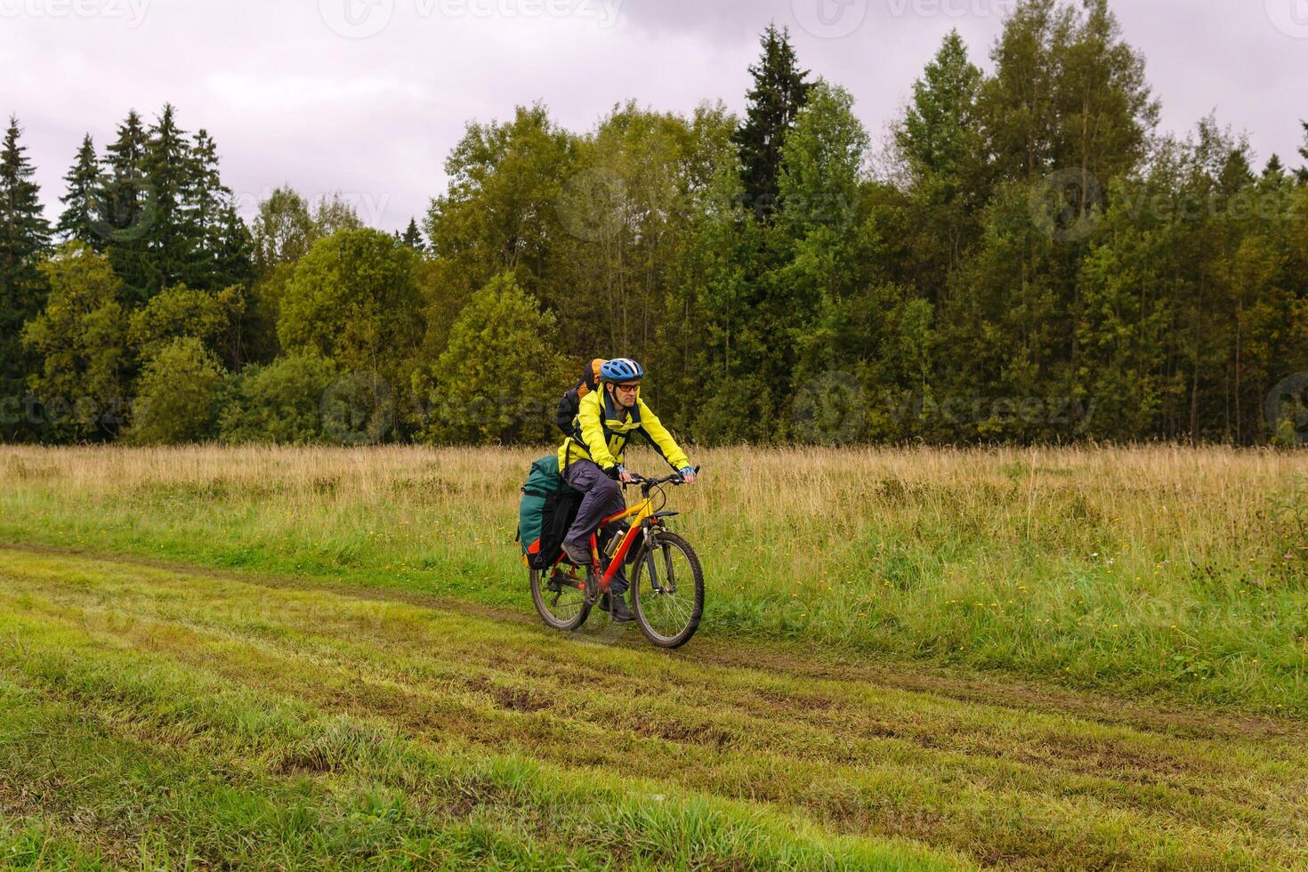 ciclismo turista paseos en un suciedad la carretera mediante un campo foto