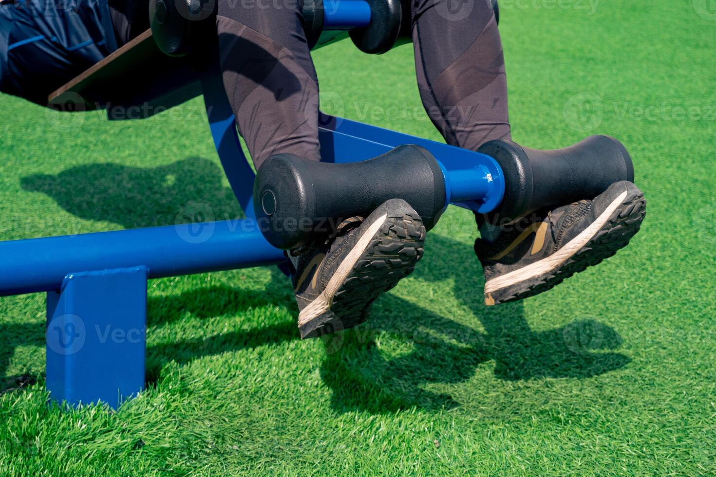 legs of a person, shakes her press using an outdoor exercise machine abdominal bench photo