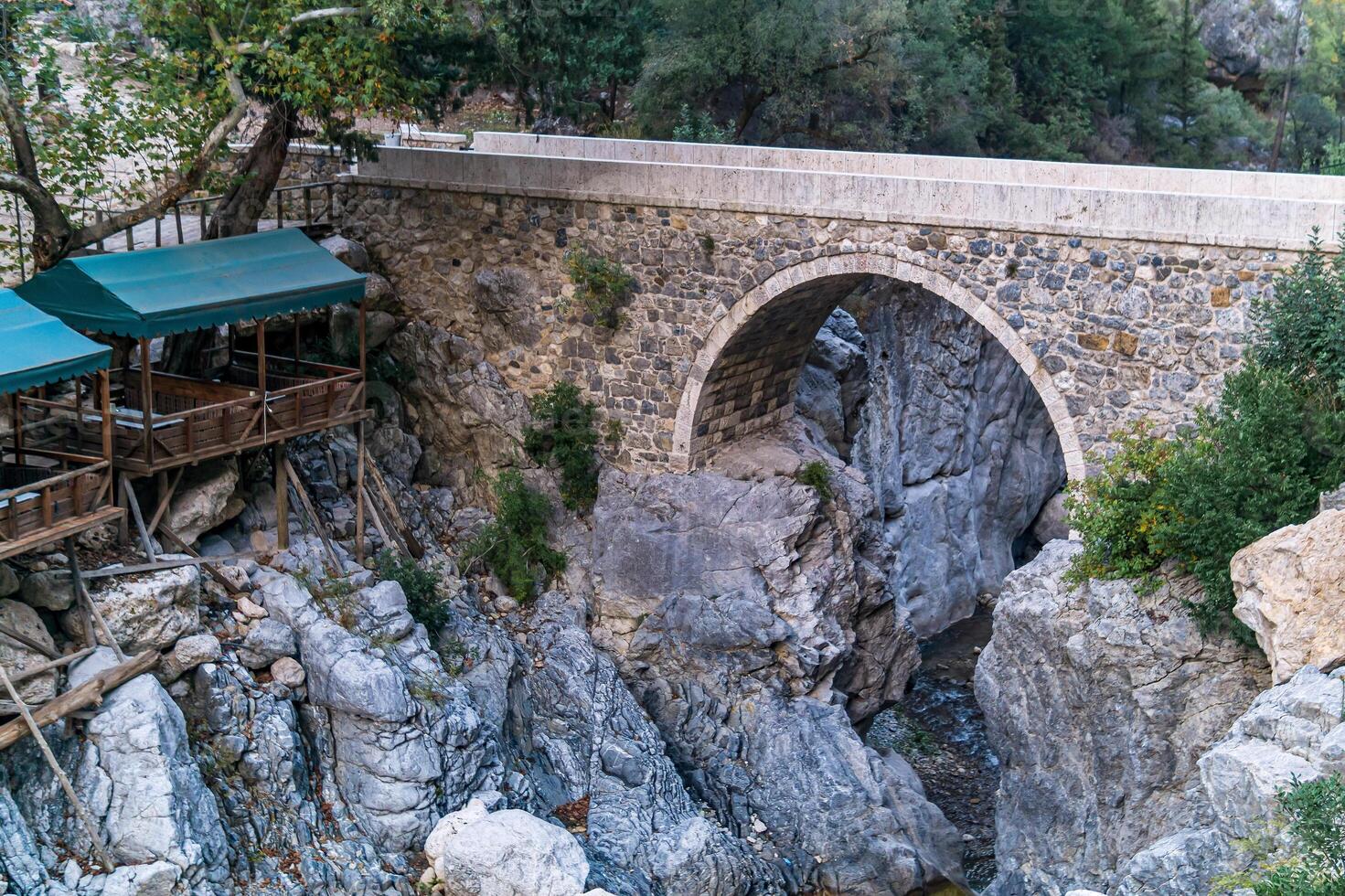 cena Kiosko para turistas siguiente a el antiguo romano puente terminado un sombreado garganta en el kesme bogazi cañón, Turquía foto