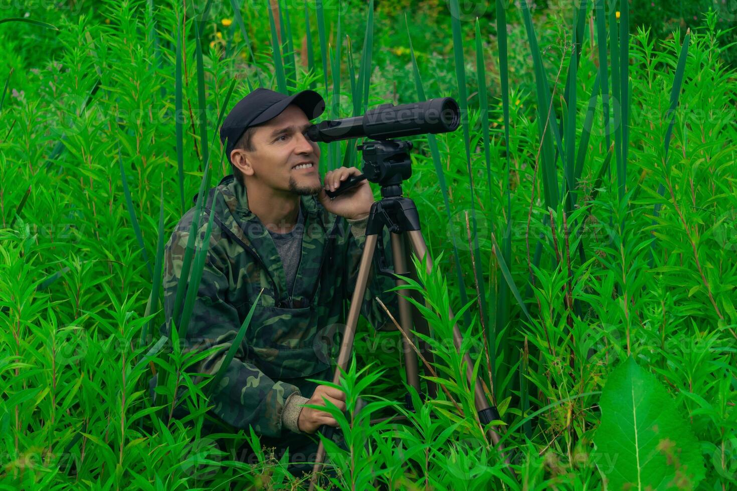 man birdwatcher makes field observation with a spotting scope photo