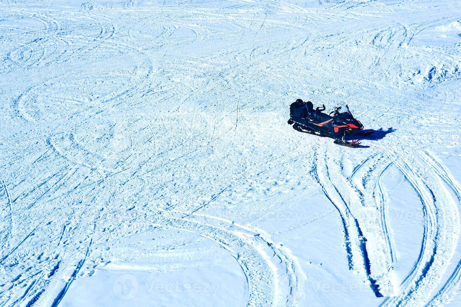 snowmobile on a snowy field with traces of many snowmachines photo