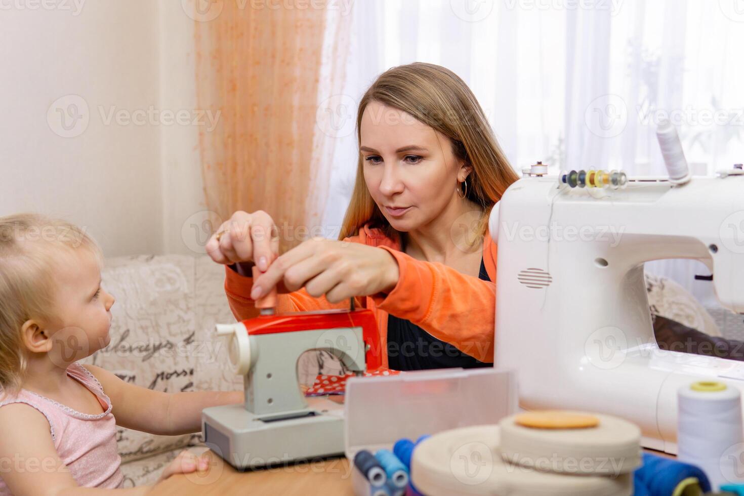 mother seamstress teaches sewing her little daughter photo