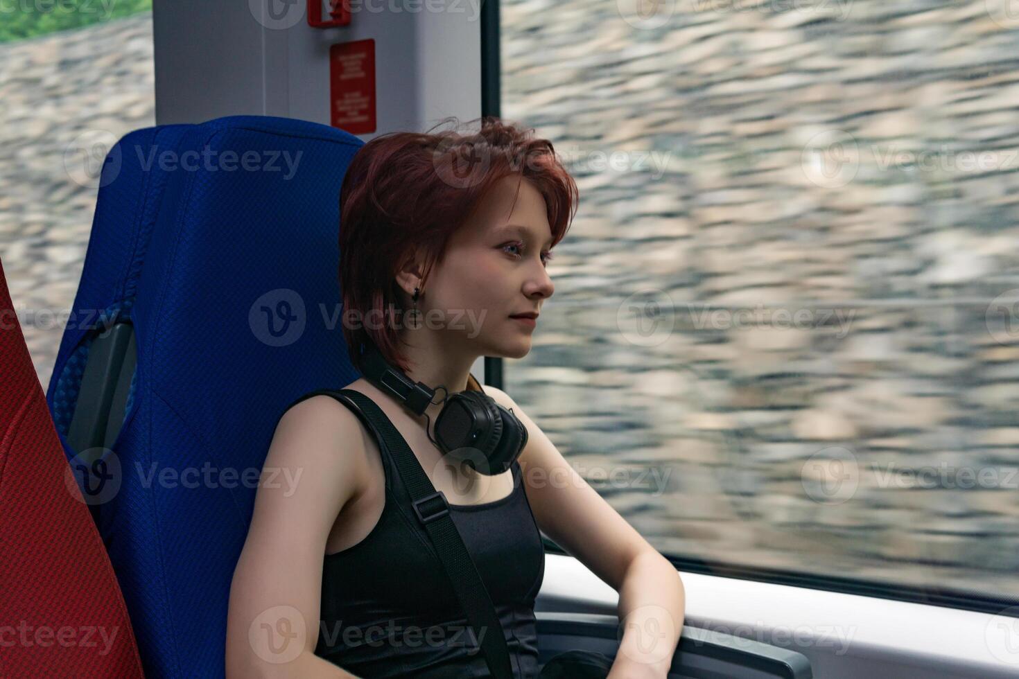 joven mujer paseos en un Moviente suburbano tren, fuera de el ventana - un tejado pared borroso en movimiento foto