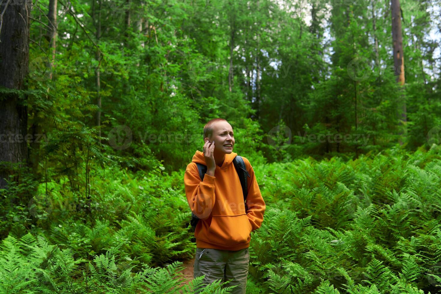 teenage girl is bitten by mosquitoes in the forest among ferns photo