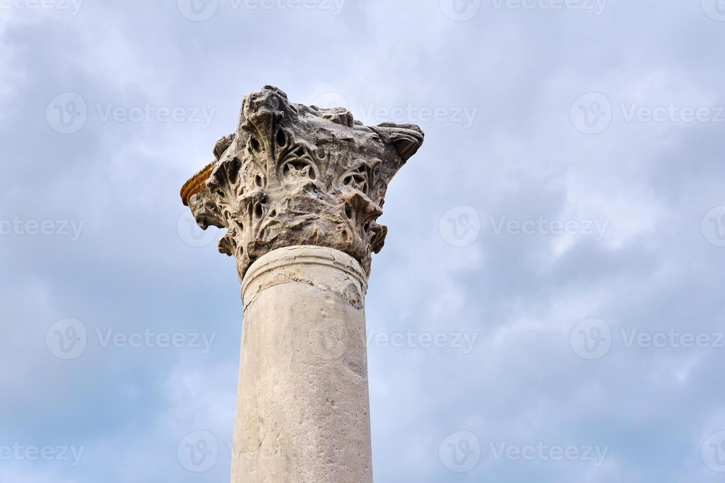 weathered capital of an antique column in the Corinthian order style against the sky photo