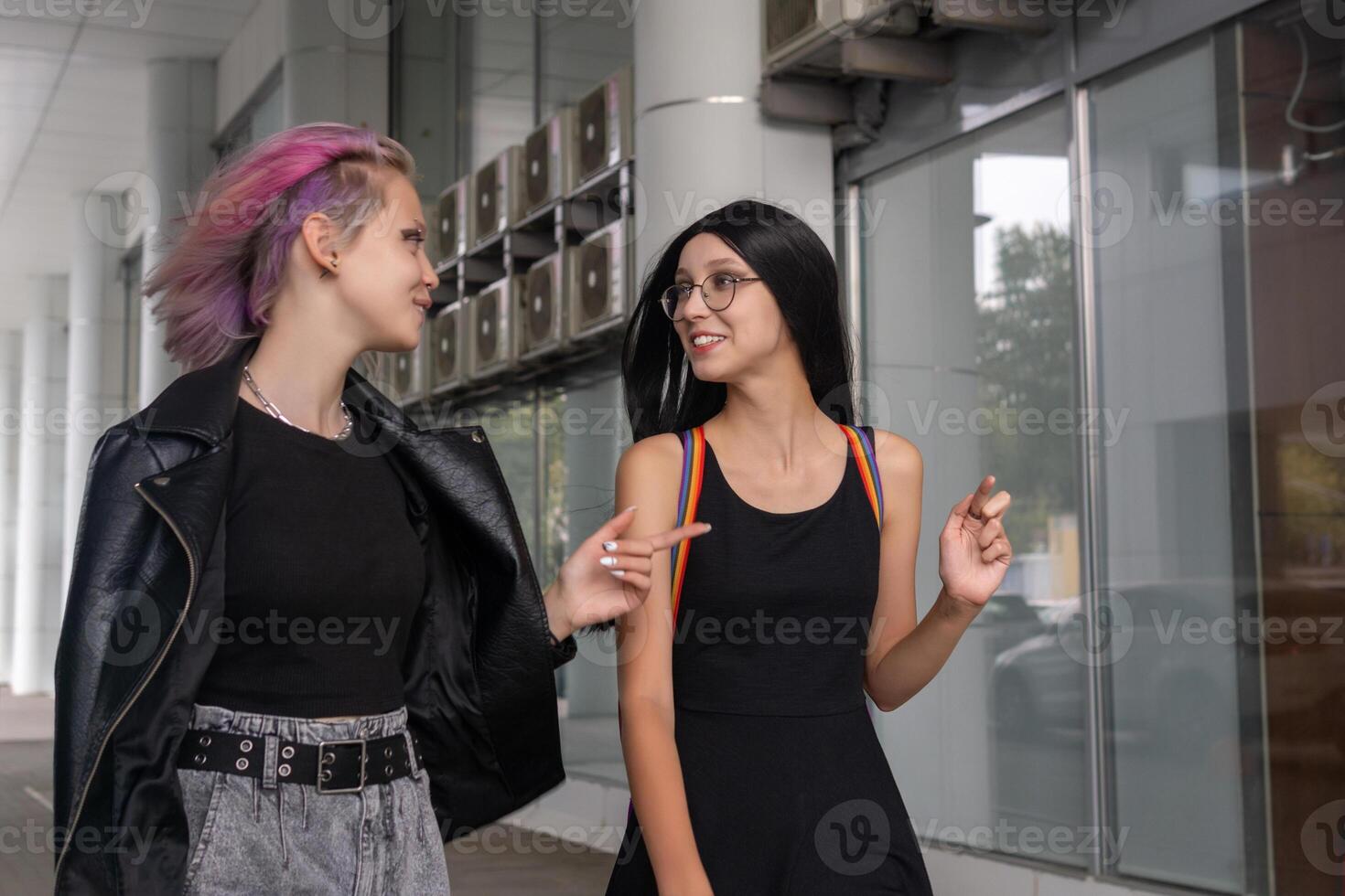 dos adolescente muchachas caminando abajo el calle y hablando foto