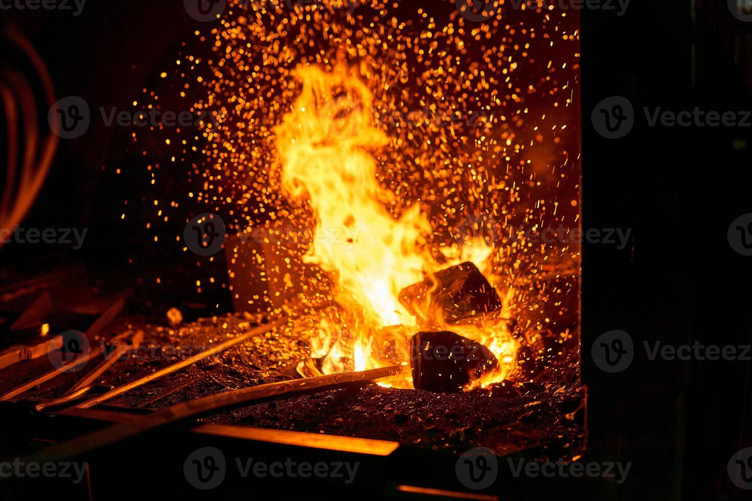 blacksmith furnace with burning fire and forging tools lying nearby photo