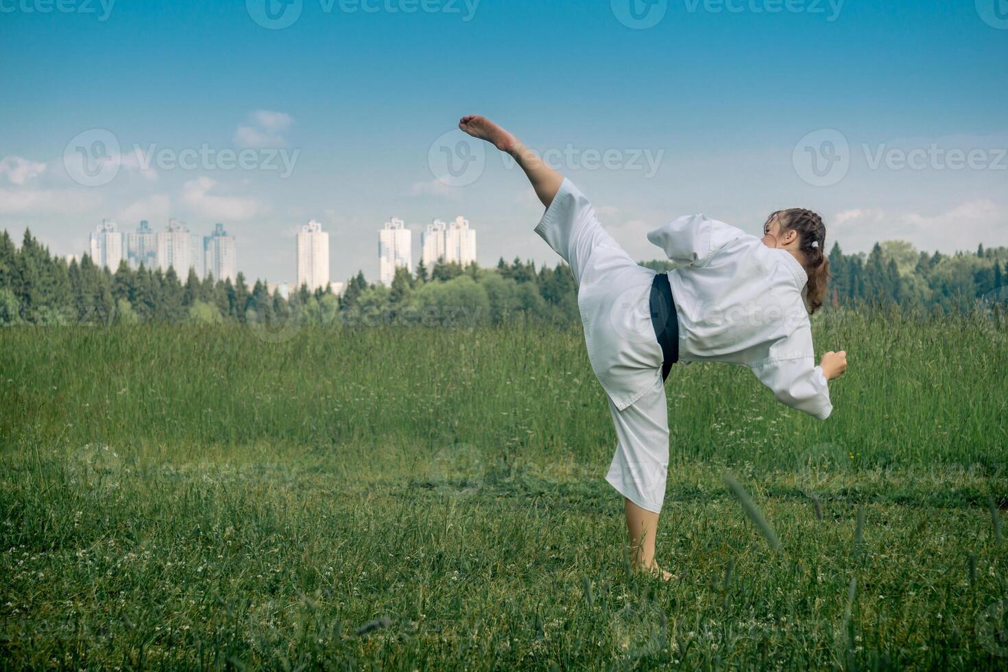 teenage girl training karate kata outdoors, performs the uro mawashi geri hook kick photo