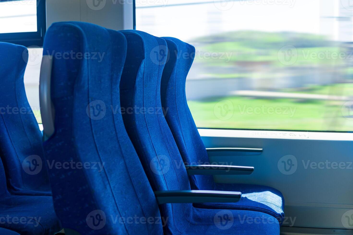 interior of commuter passenger train car, row of chairs and a motion-blurred landscape outside the window photo