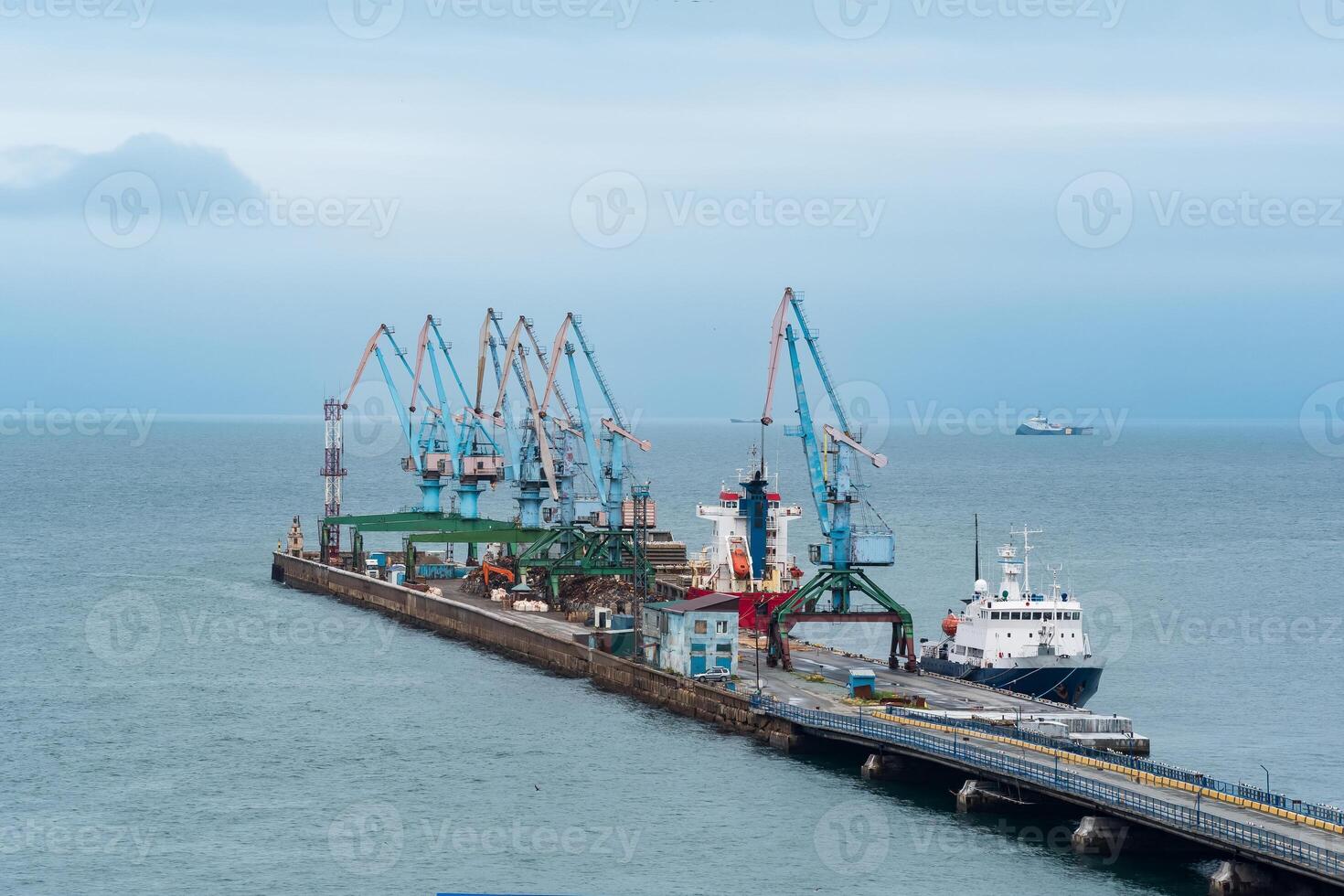 cargo berth with port cranes and moored ships against the backdrop of the open sea photo