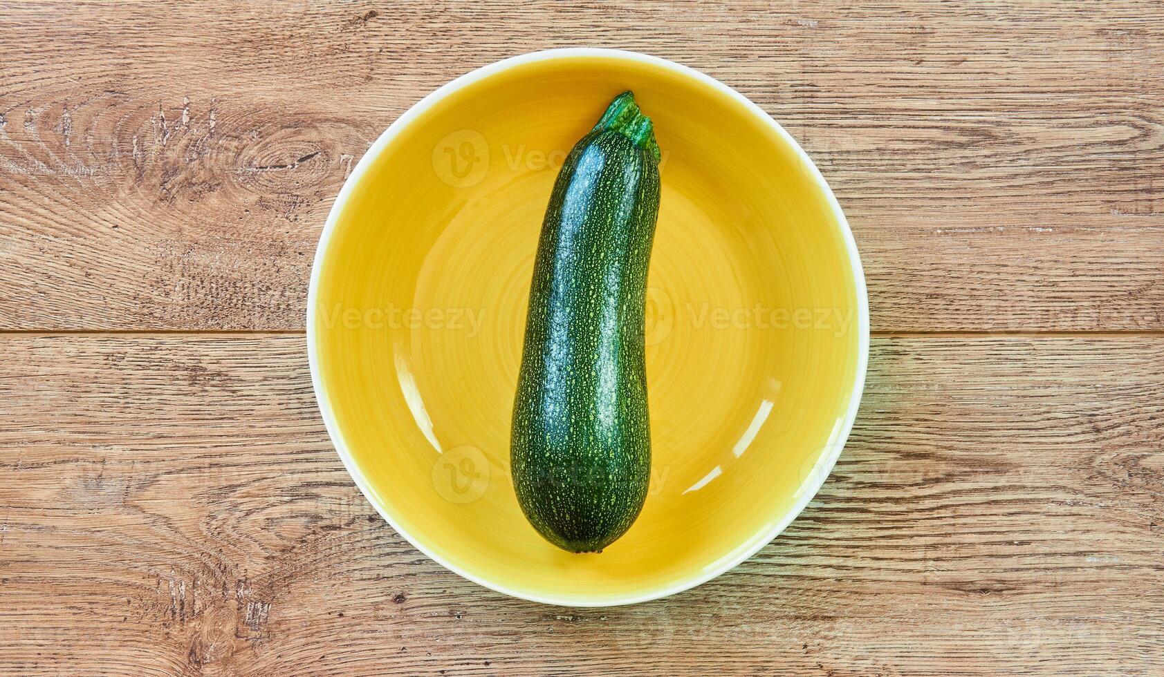 verde calabacín squash con estampado piel en un amarillo plato en un de madera mesa foto