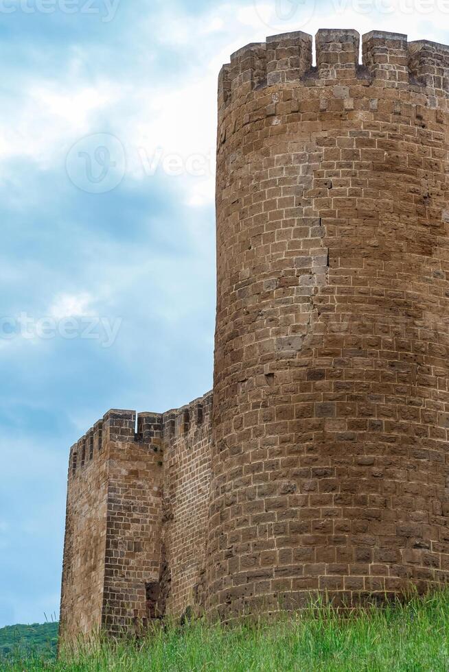 torre de un medieval fortaleza encima un muralla descuidado con césped en contra el cielo, naryn-kala ciudadela en derbente foto