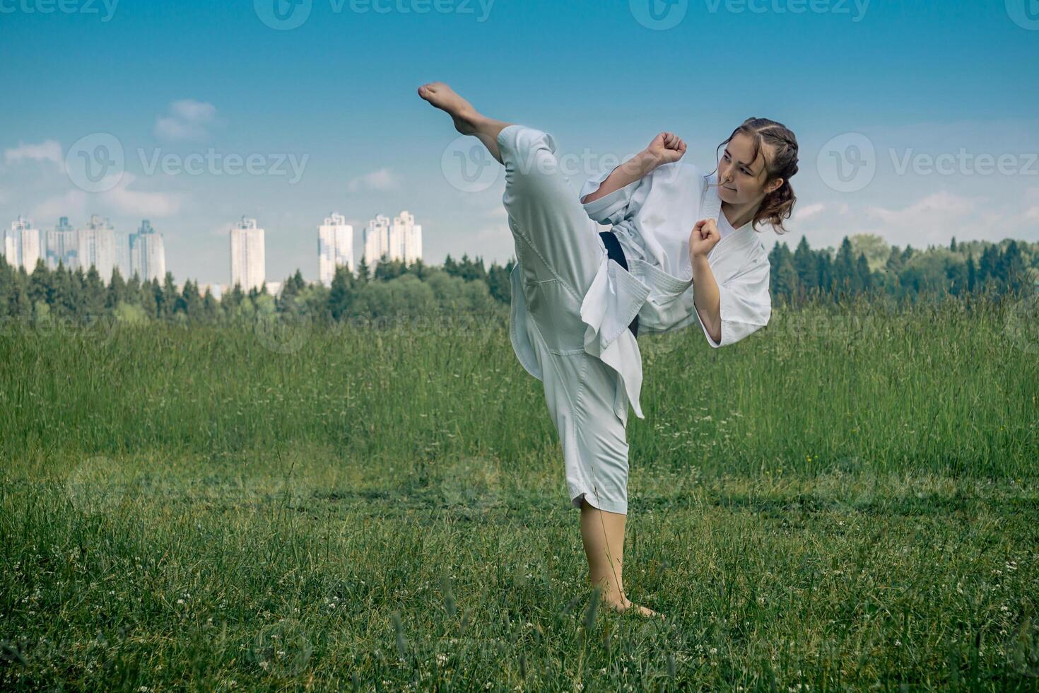 teenage girl training karate kata outdoors, performs the uro mawashi geri hook kick photo