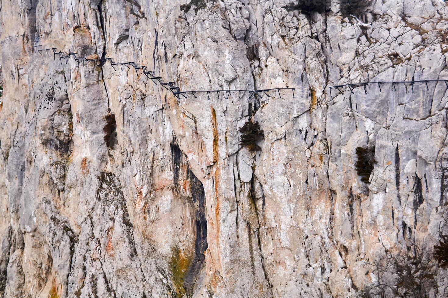 background - the surface of a huge cliff with a destroyed hanging path on it photo