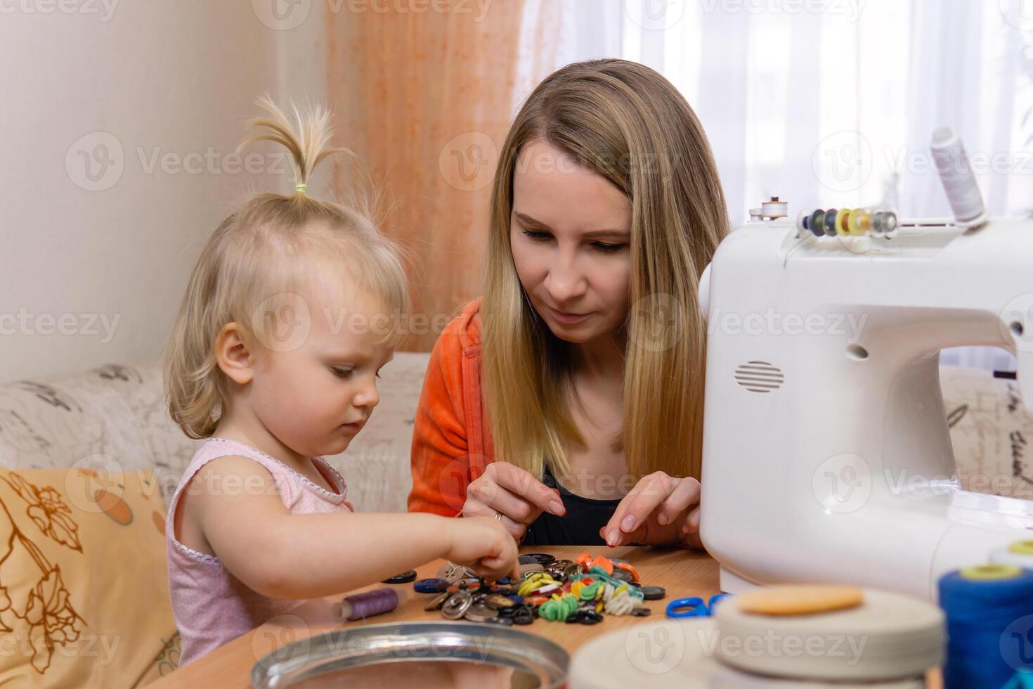 seamstress woman interrupted work and communicates with little daughter photo
