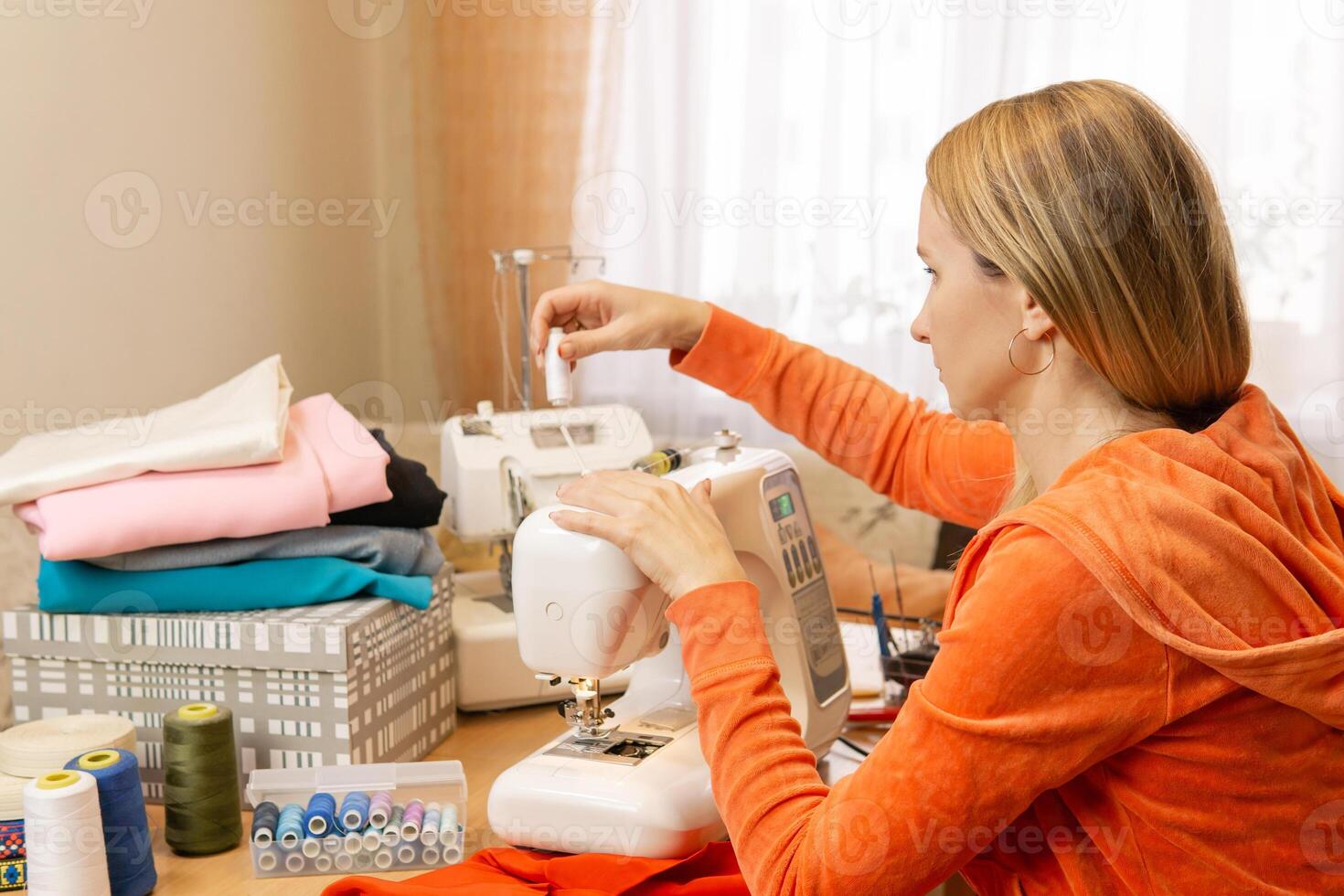 seamstress equips spool of thread on a home sewing machine photo