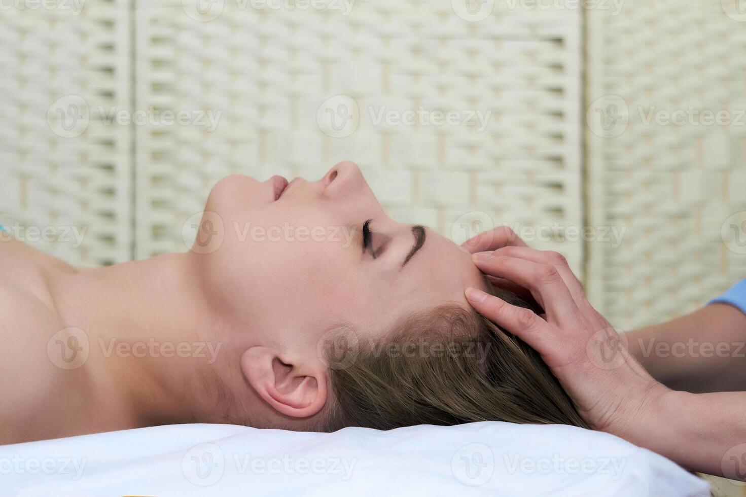 beautiful young woman getting facial massage in the spa salon, close-up portrait, side view photo