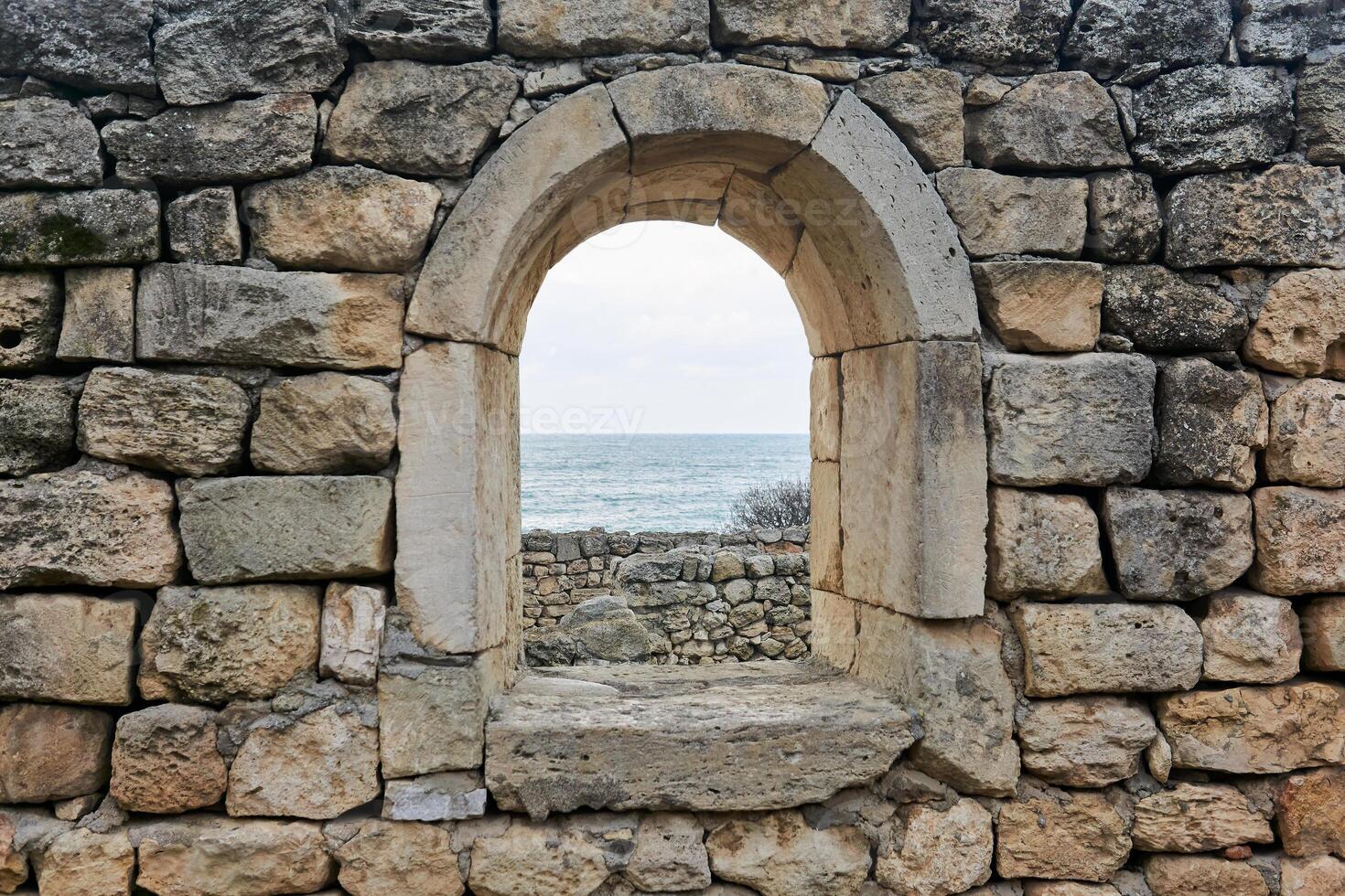 window opening in the ruins of an antique wall, behind which you can see the sea photo