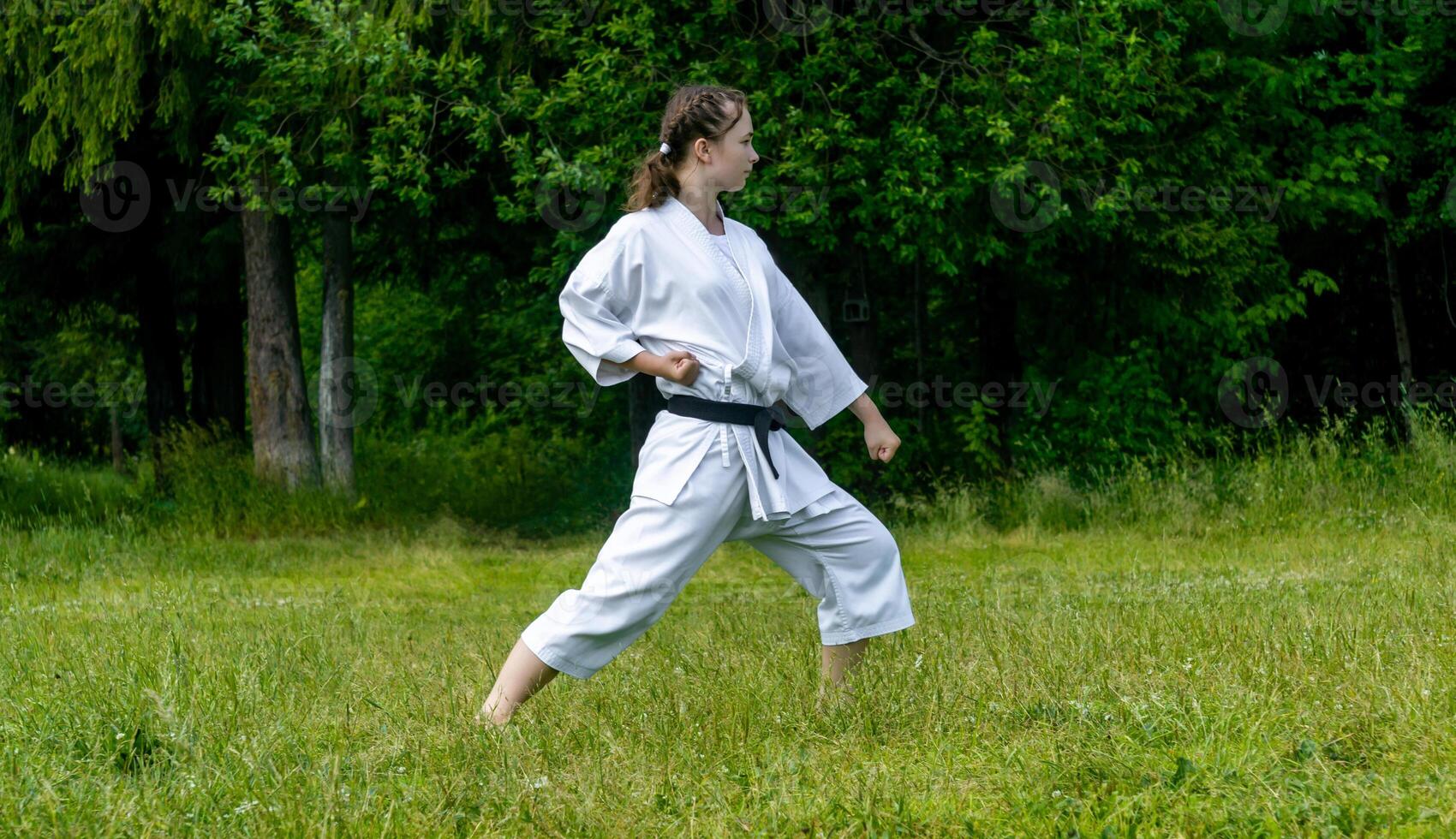 teenage girl training karate kata outdoors, performs gedan-barai or downward block photo