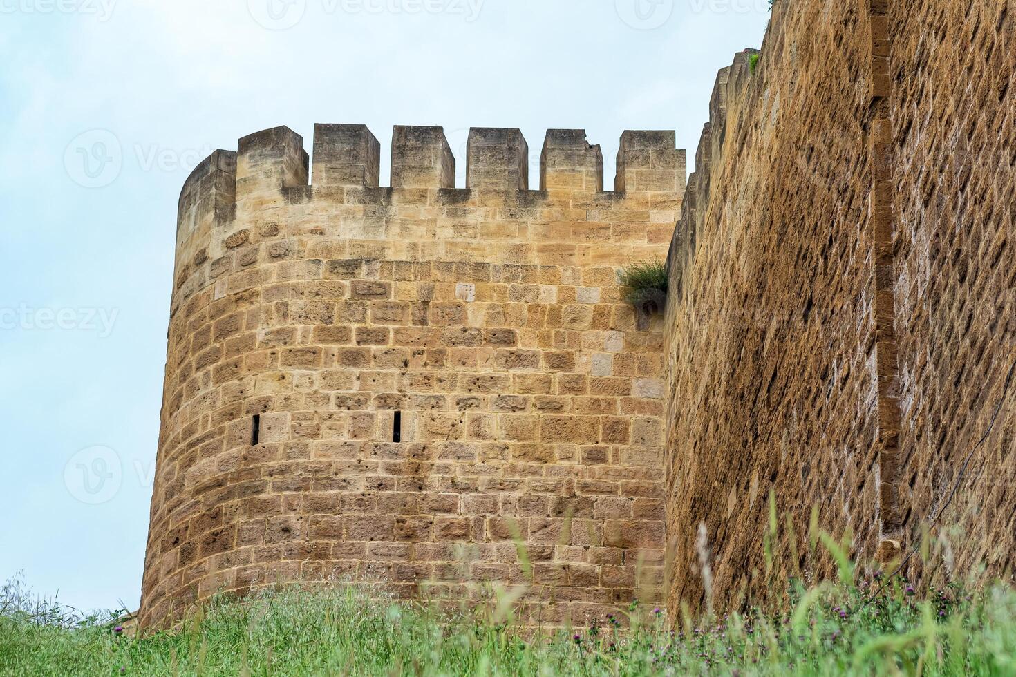 bastion of a medieval fortress above a rampart overgrown with grass against the sky, Naryn-Kala citadel in Derbent photo