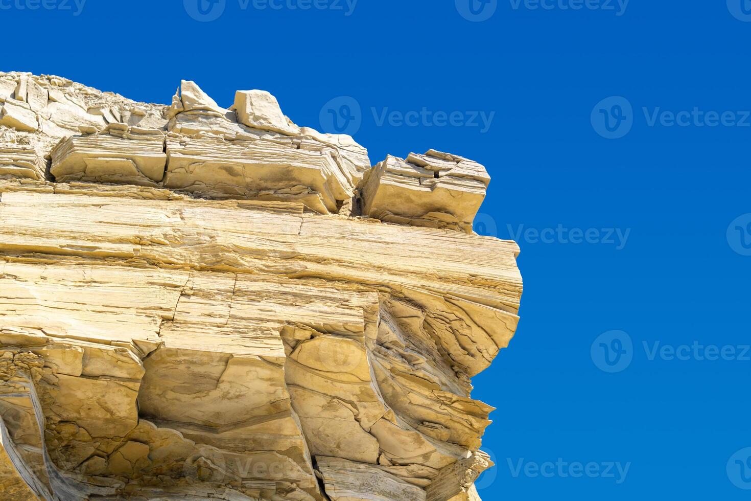 layered limestone cliff against blue sky photo