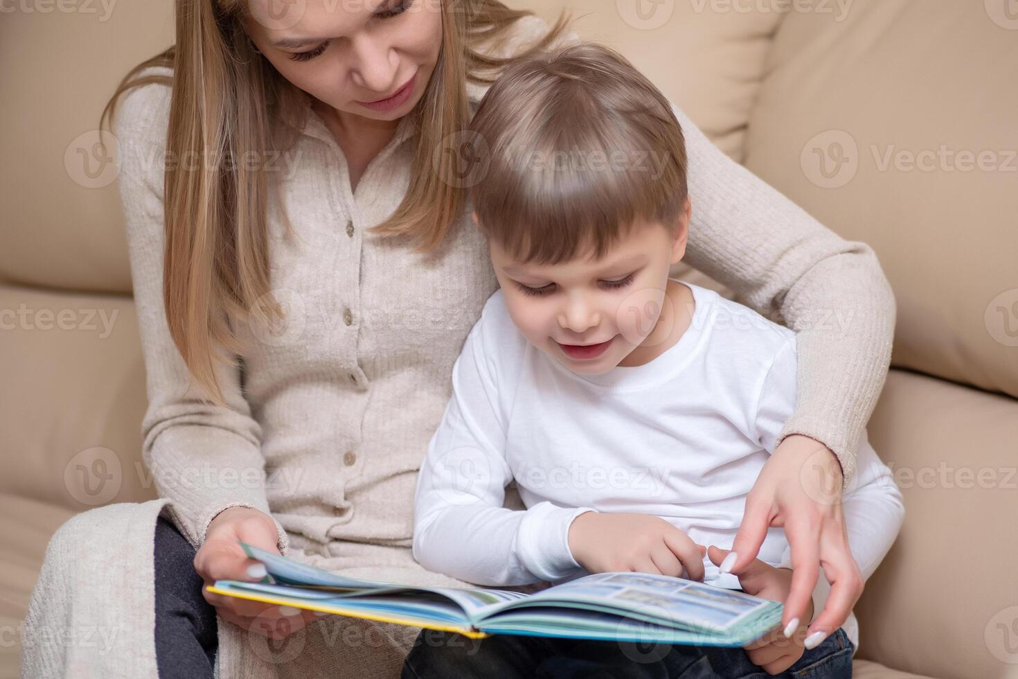 woman reading book to child indoors photo