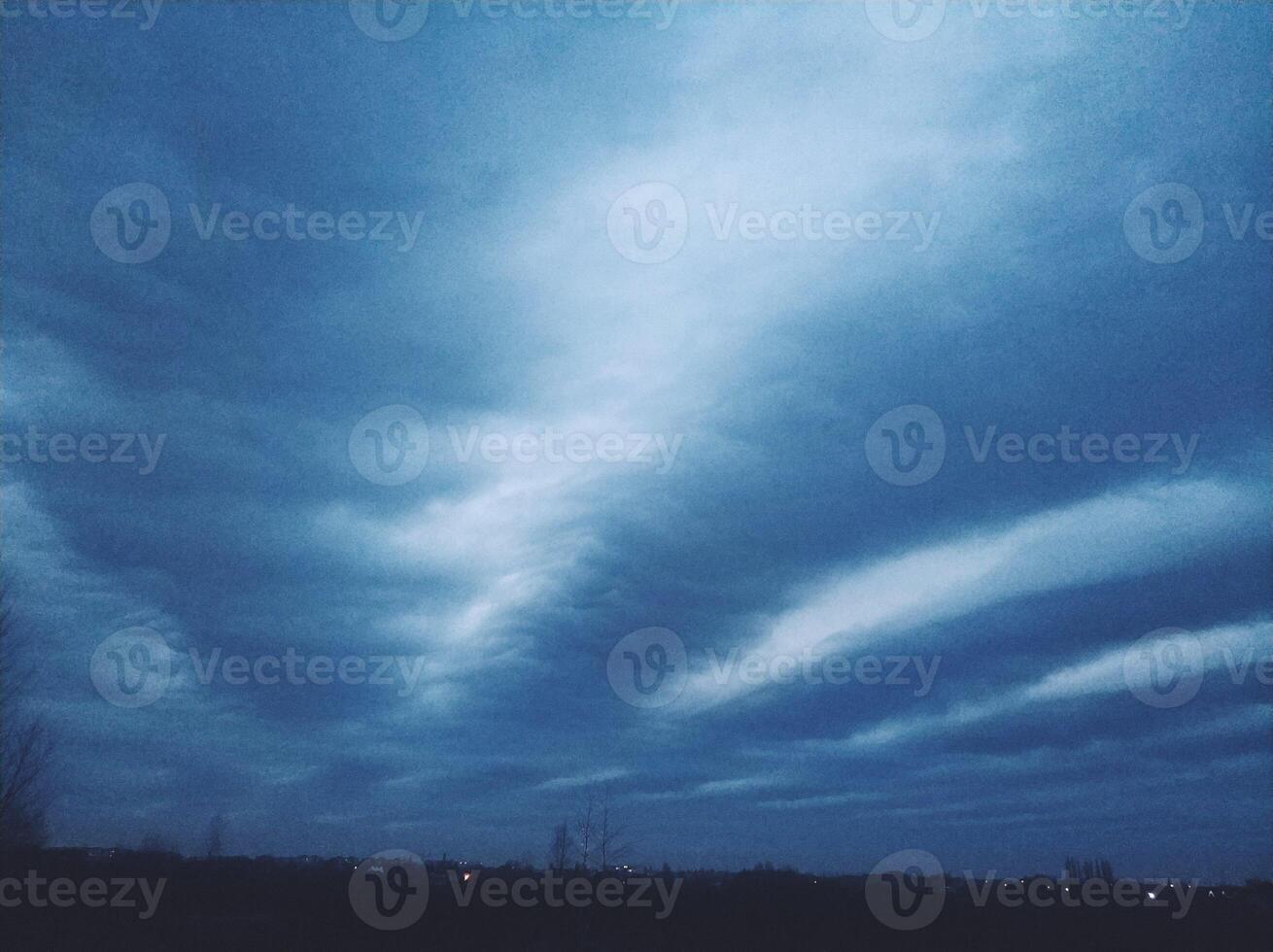 Incredibly bright evening blue sky with long clouds stretching across the sky photo