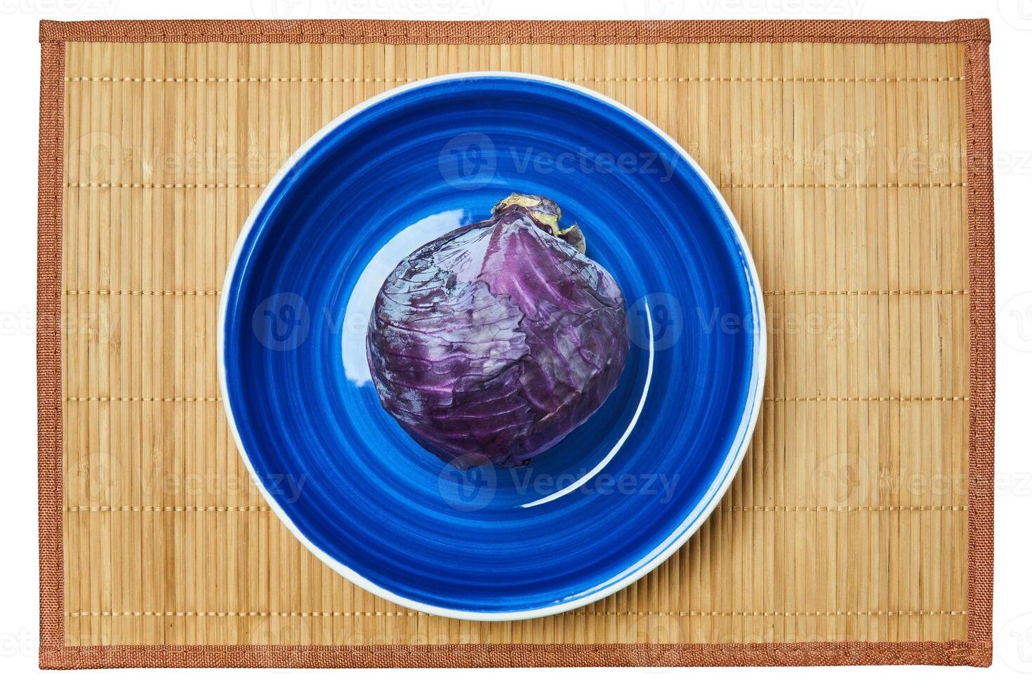 púrpura cabeza de rojo repollo en un azul plato en un caña servicio estera foto