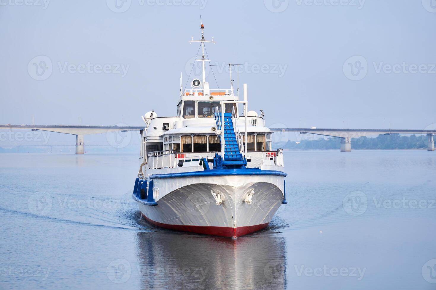 small passenger motorship on the river and road bridge in the morning haze in the background photo