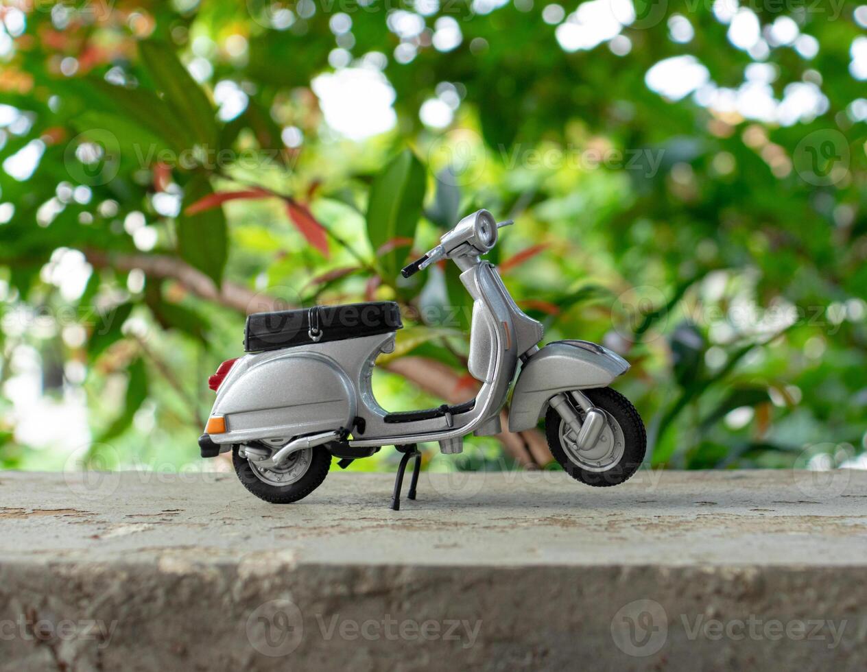 Miniature classic scooter on the cement floor with nature background. After some edits. photo