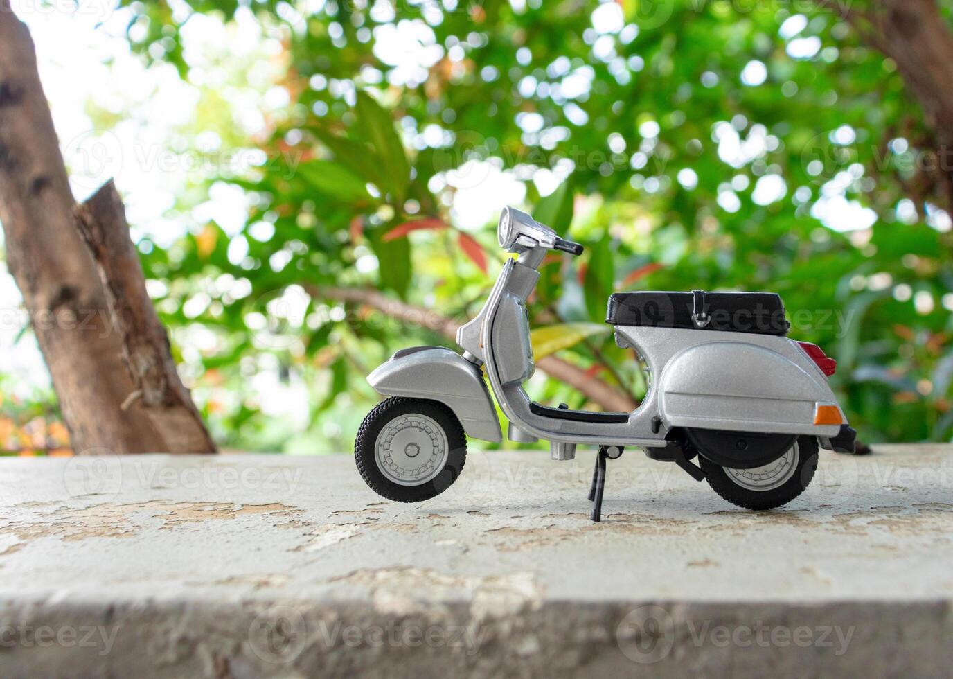 Miniature classic scooter on the cement floor with nature background. After some edits. photo