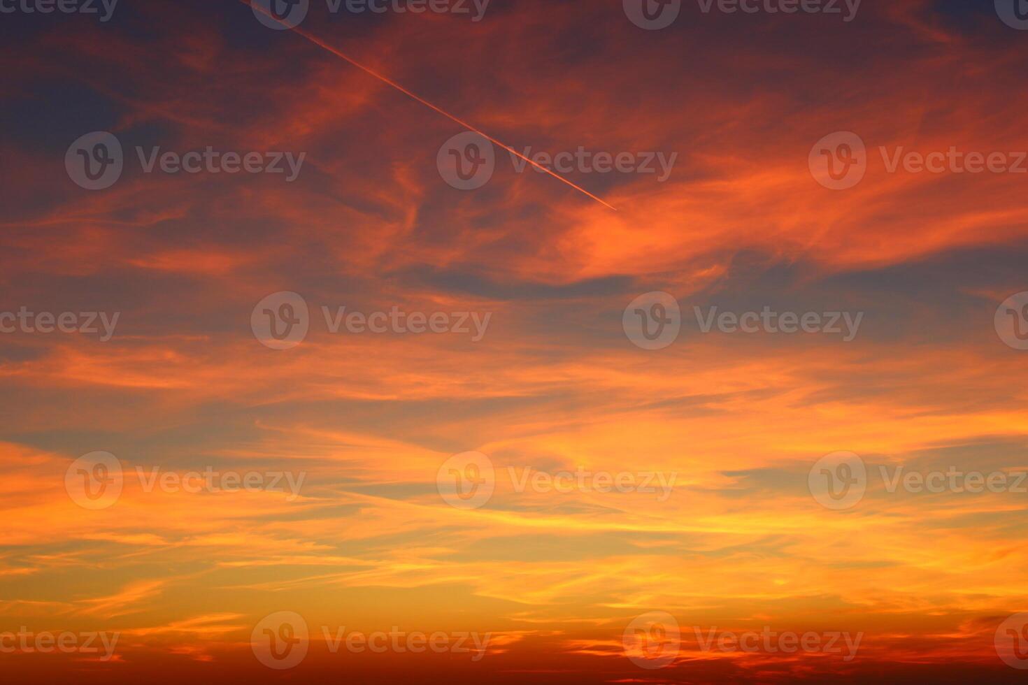 airplane and its trail in the sky. clouds and different color tones in the sky at sunset. Amazing and incredible sunset. photo