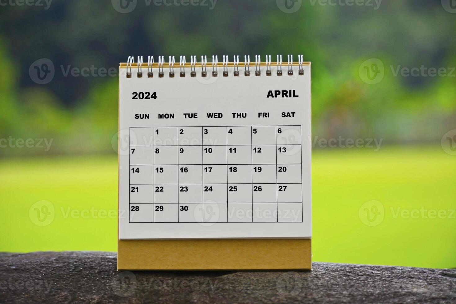 April 2024 white calendar with green blurred background. photo