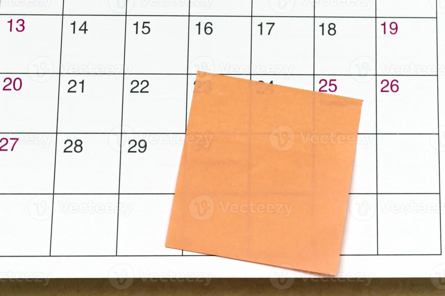 Orange paper sticky note on calendar. Copy space. photo