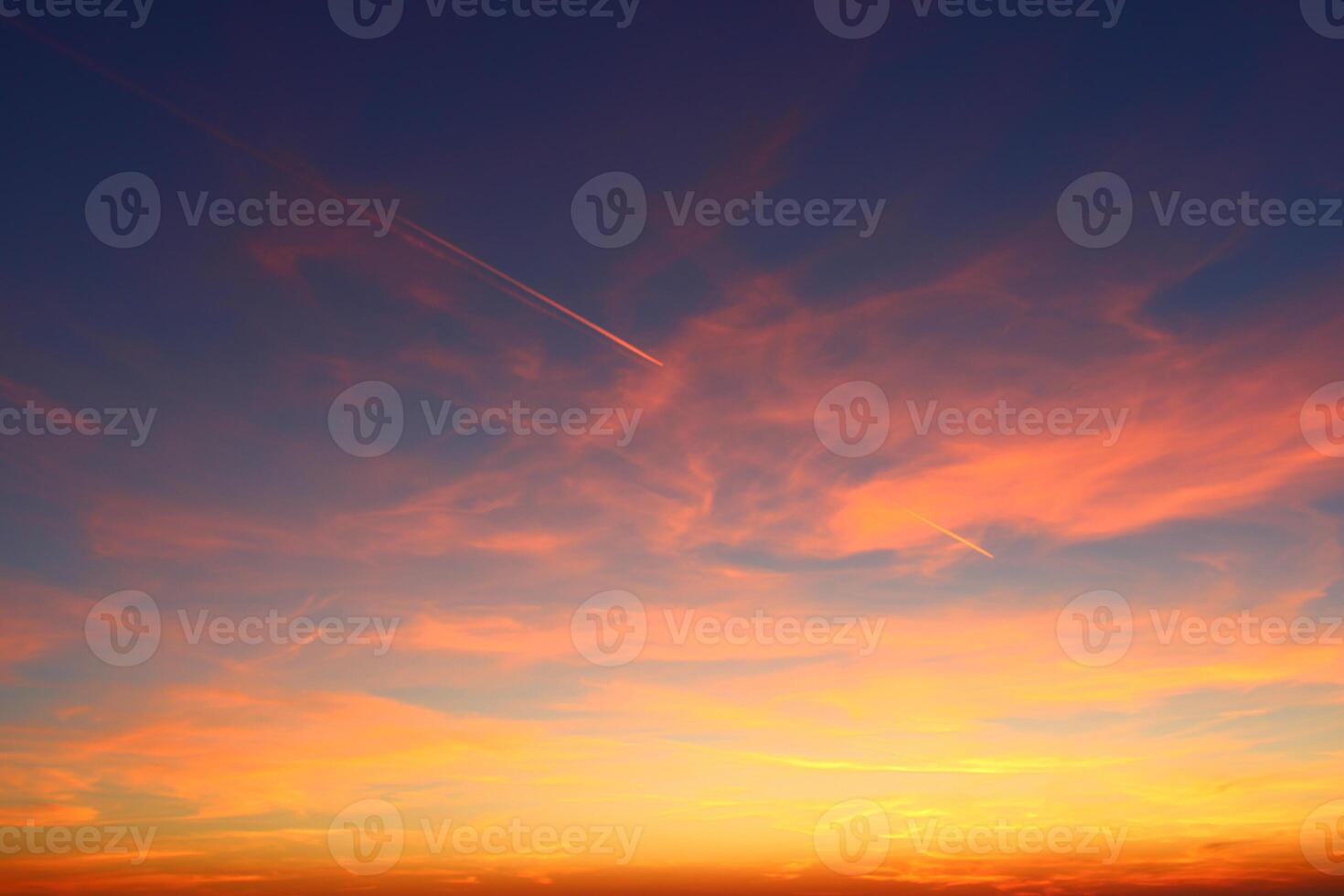 airplane and its trail in the sky. clouds and different color tones in the sky at sunset. Amazing and incredible sunset. photo