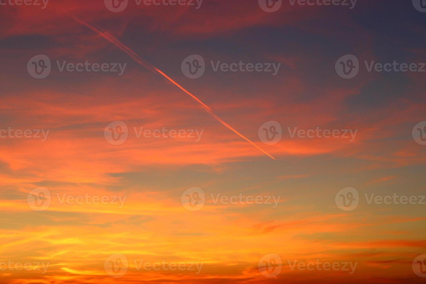 airplane and its trail in the sky. clouds and different color tones in the sky at sunset. Amazing and incredible sunset. photo