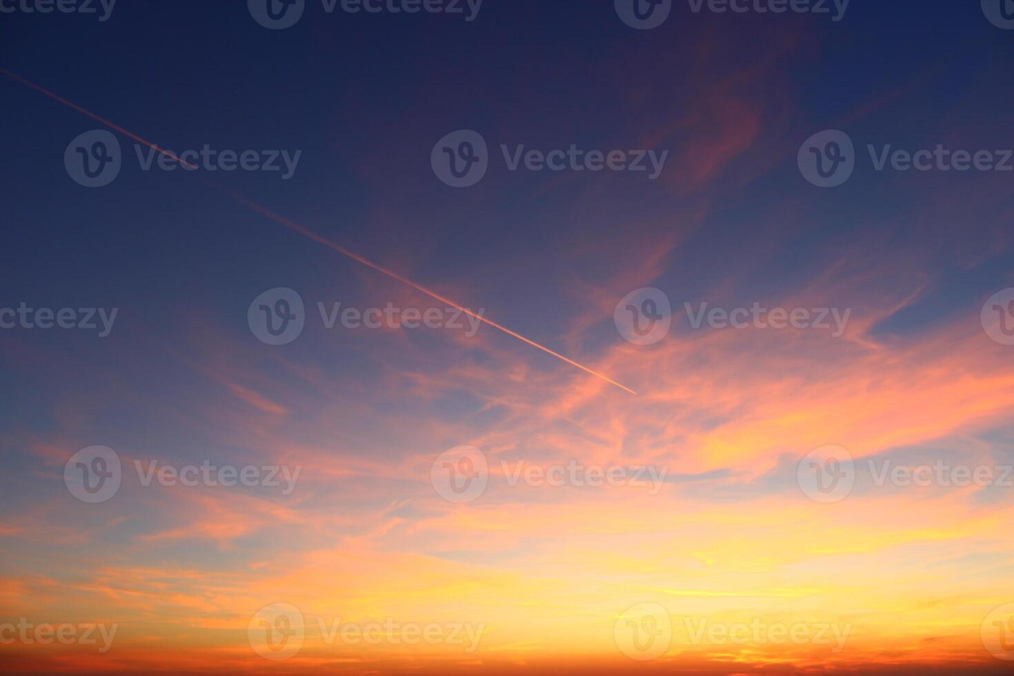 airplane and its trail in the sky. clouds and different color tones in the sky at sunset. Amazing and incredible sunset. photo