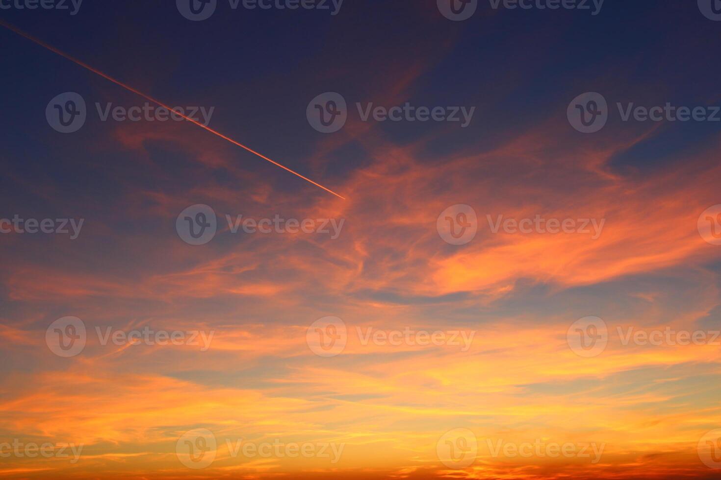 airplane and its trail in the sky. clouds and different color tones in the sky at sunset. Amazing and incredible sunset. photo