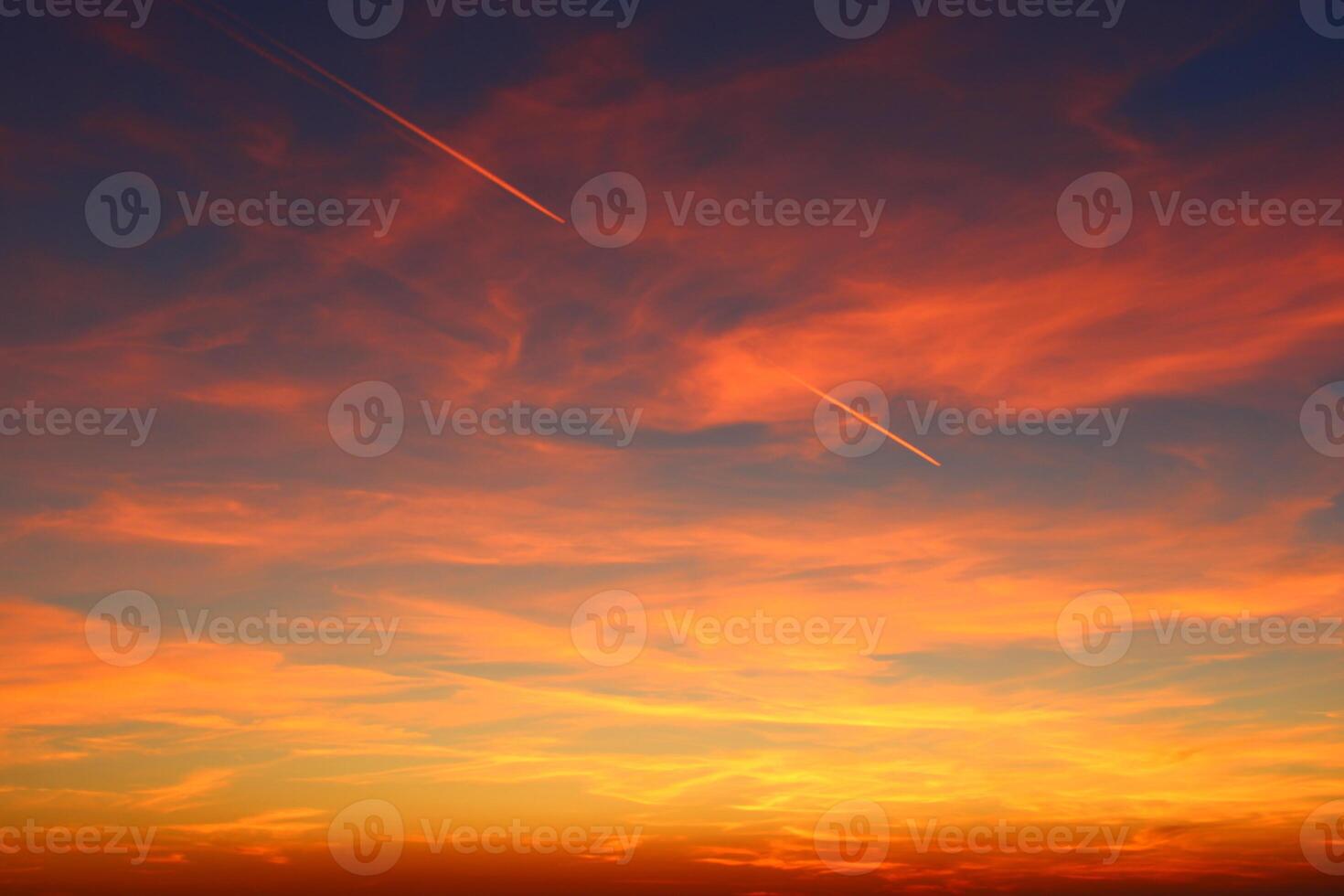 airplane and its trail in the sky. clouds and different color tones in the sky at sunset. Amazing and incredible sunset. photo