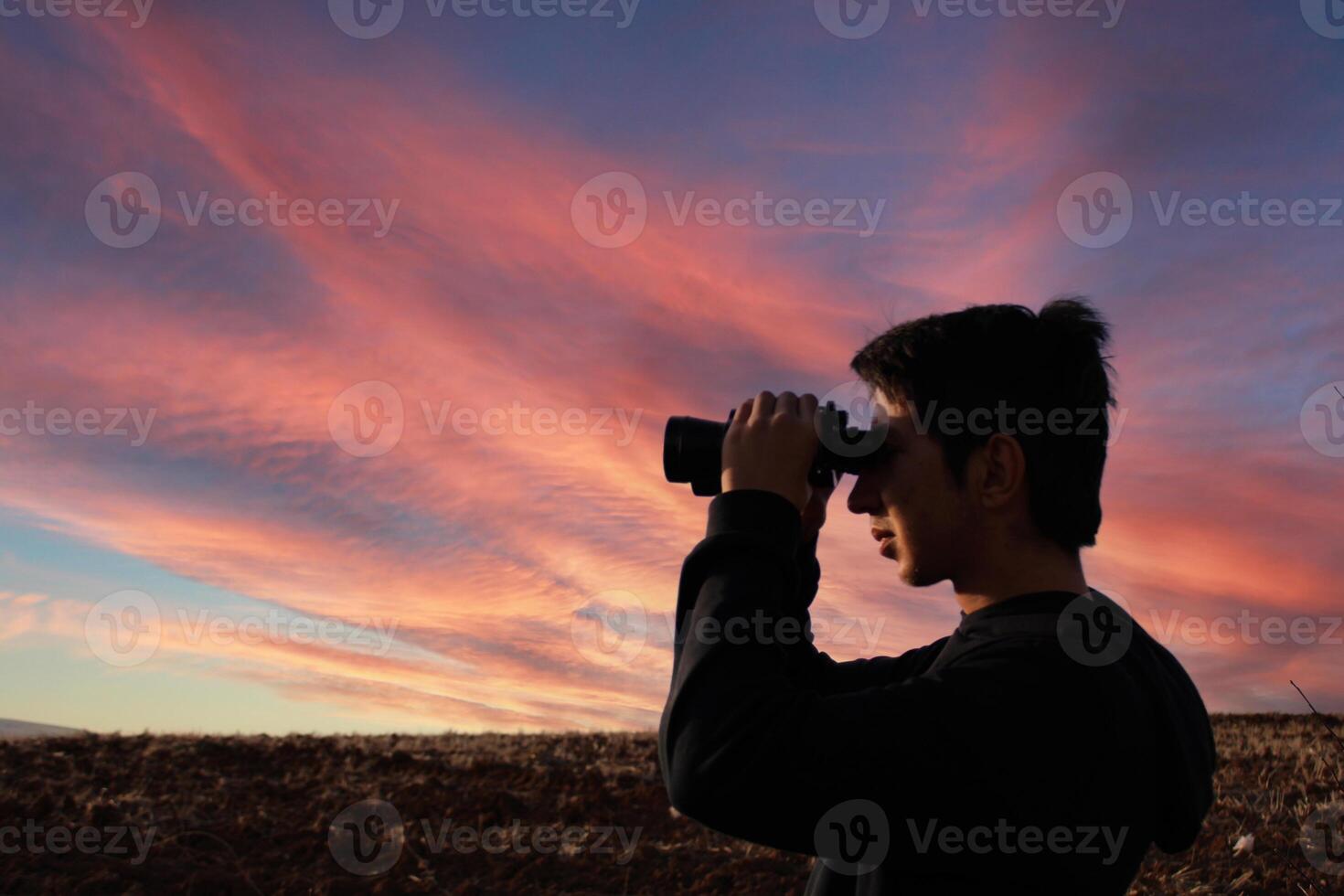 A young man watching prayer through binoculars. Observe and spying. photo