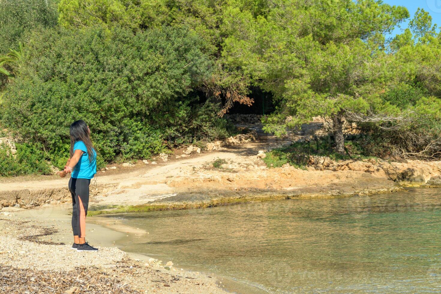 latina mujer, en el apuntalar de el playa mirando a el mar respiración profundamente foto