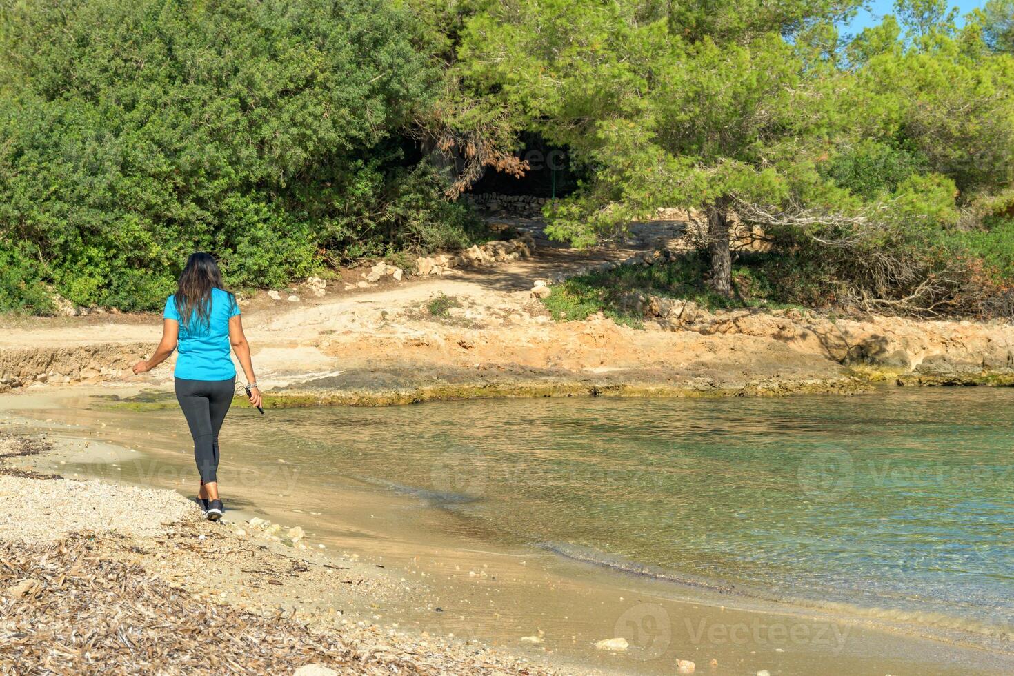 Latina sportswoman, walking along the shore of a Mediterranean island beach photo