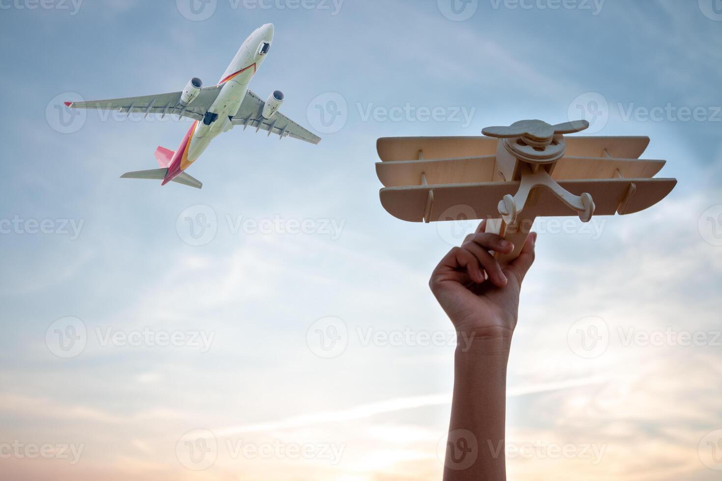 Child Holding a Wooden Airplane Model High in the Sky photo
