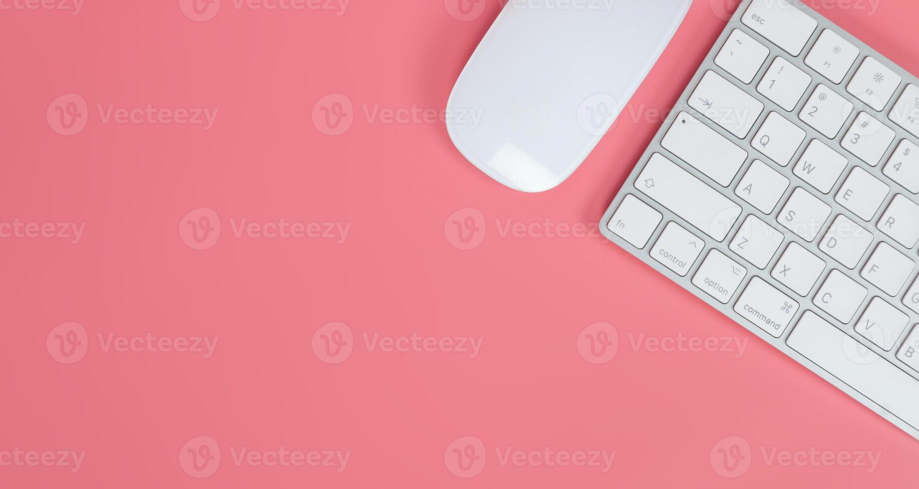 Flat lay, top view office table desk. Workspace with keyboard and mouse on pink background photo