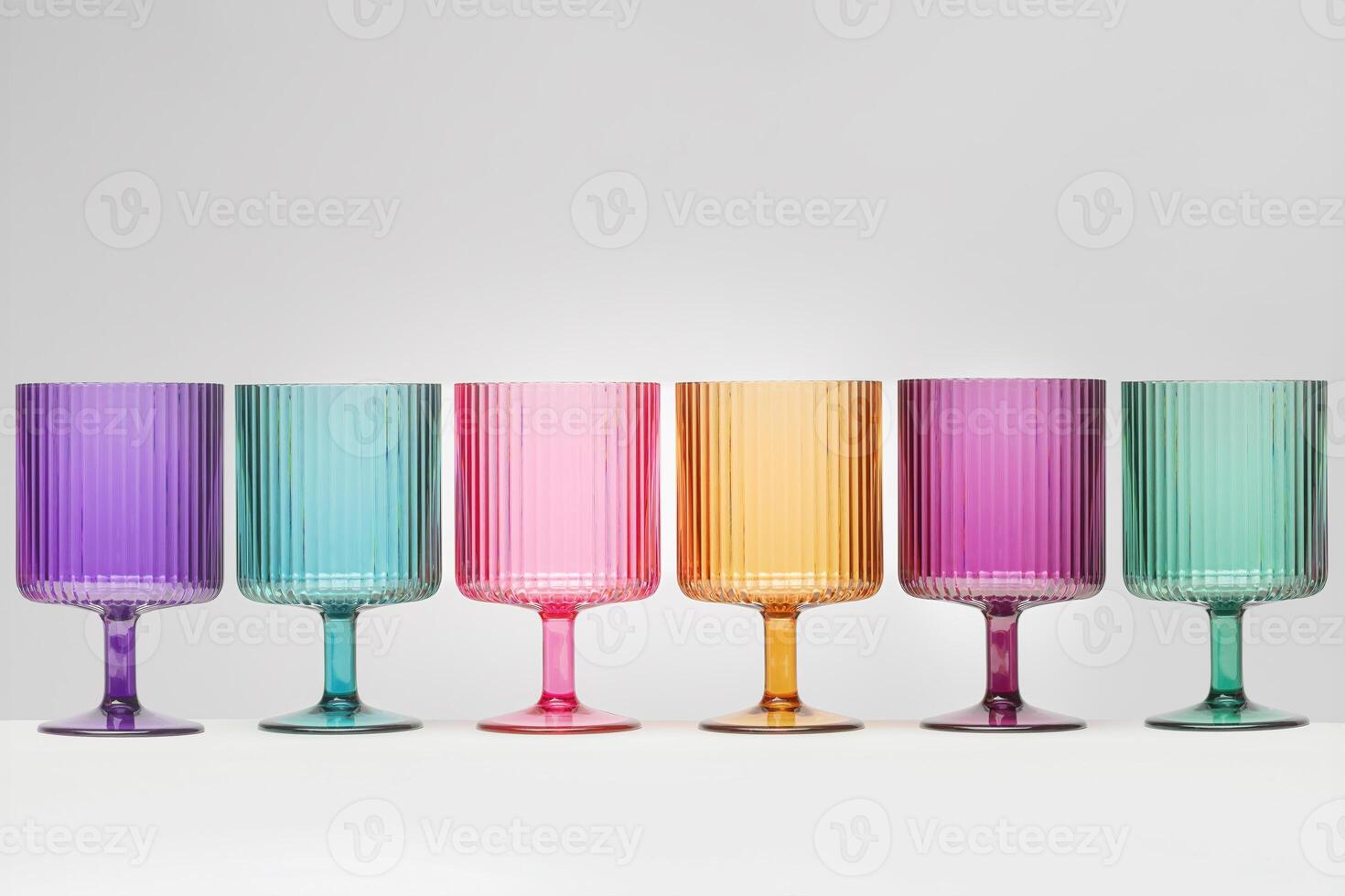 Multi cColored Wine Glasses Lined up in a Row on a White Background photo