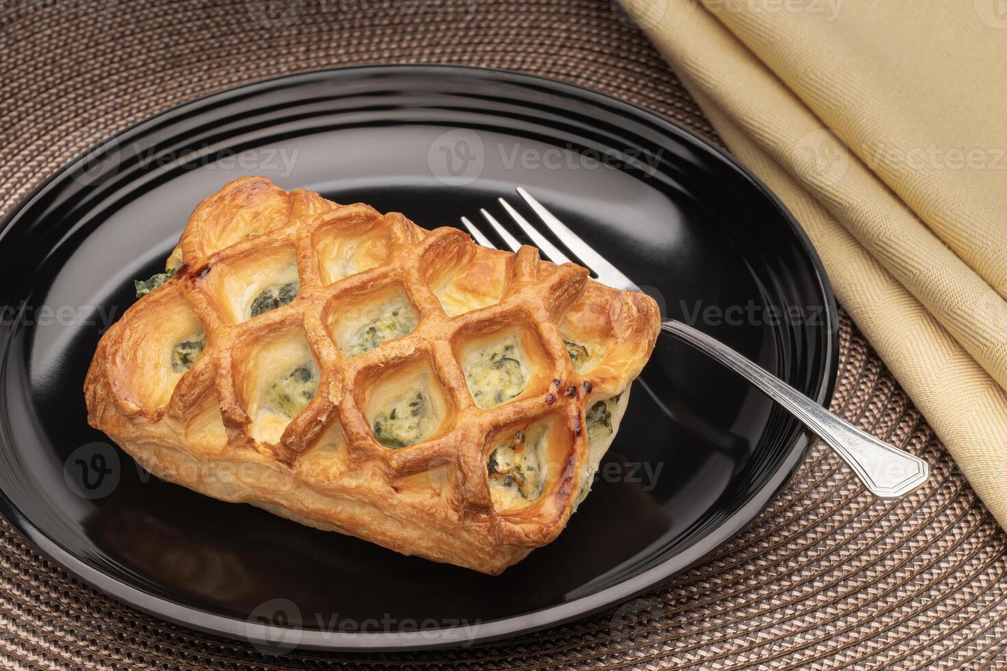 Spinich and cheese pastry on a black plate photo