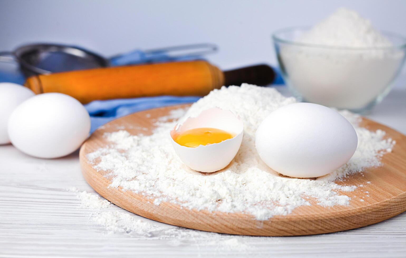 Baking ingredients flour, eggs and rolling pin on a table. Close-up. photo