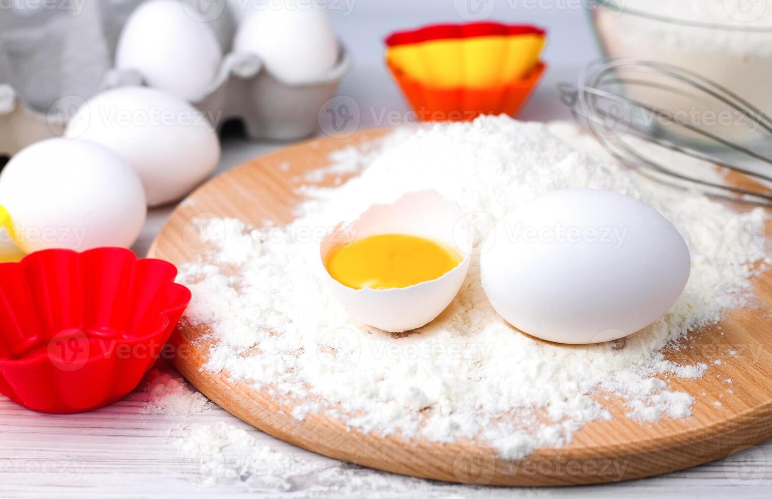 Ingredients for baking muffins and cupcakes flour, eggs and colourful silicone form on a table. Close-up. photo