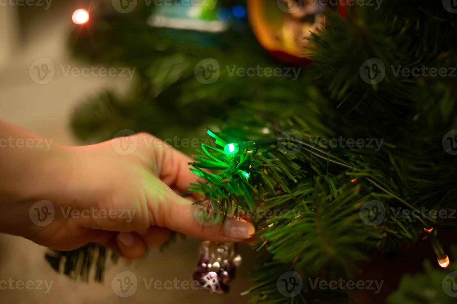 Decorating Christmas tree, close up, copy space. Merry Christmas and Happy New Year. Women hands decorate the Christmas tree with balls and toys photo